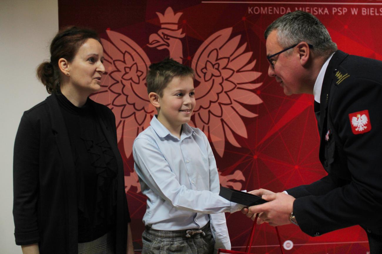 zastępca Śląskiego Komendanta PSP wręcza chłopcu medal