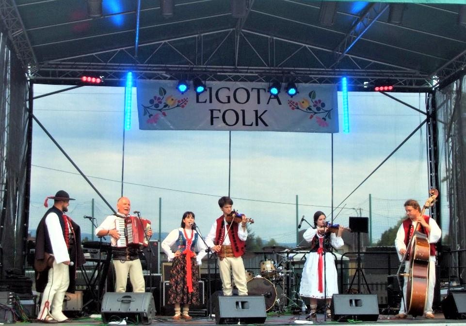 Zespół muzyczny na scenie pod banerem Logota Folk