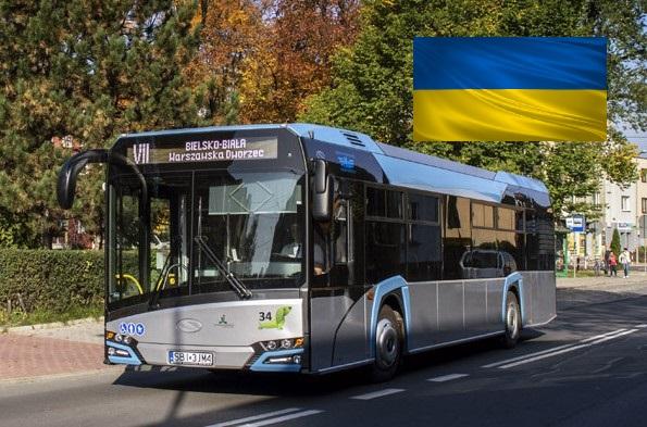 Autobus PKM jadący przez miasto, w rogu zdjęcia flaga Ukrainy
