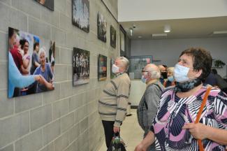 pensjonariusze oglądają wystawę - zdjęcia na ścianie 