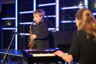 Młody muzyk gra na saksofonie z akompaniamentem fortepianu