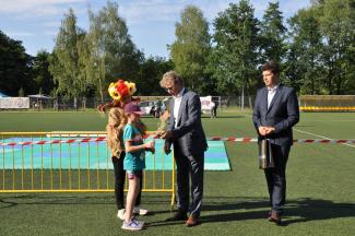 Burmistrz z zastępcą wręczają nagrody dziecku na boisku