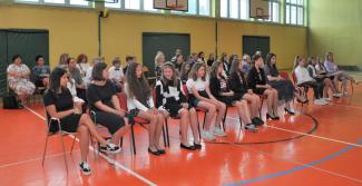 Laureaci siedzący na krzesłach ustawionych na sali gimnastycznej