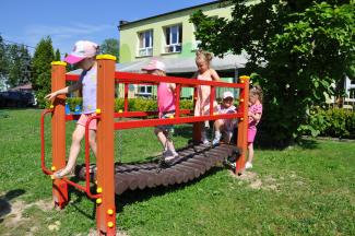 Dzieci bawiące się na mostku w otoczeniu zieleni