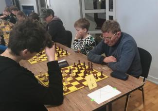 zawodnicy siędzący przy stołach, turniej szachowy