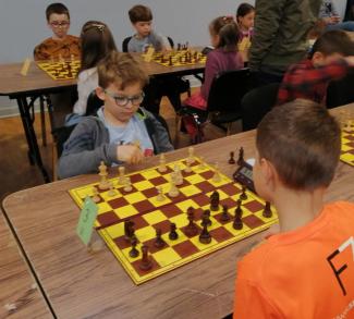 turniej ligi szachowej, chłopcy siedzący przy stołach grają w szachy