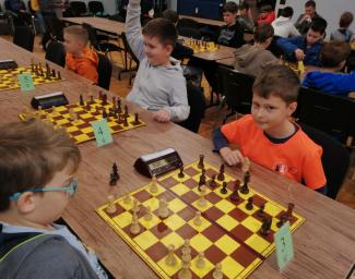 turniej ligi szachowej, dzieci siedzące przy stołach grają w szachy
