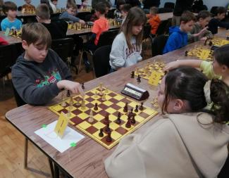 turniej ligi szachowej, zawodnicy siedzący przy stołach grają w szachy