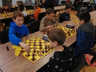 turniej ligi szachowej, chłopcy siedzący przy stołach grają w szachy