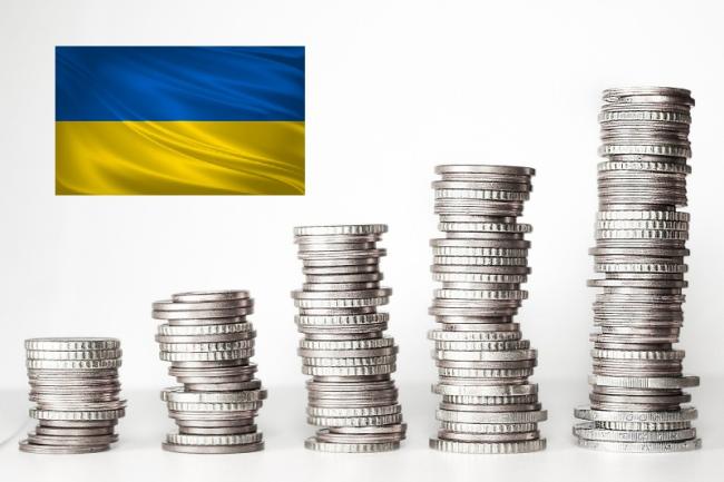 Monety w stosach, od najmniejszego do największego, z flagą Ukrainy