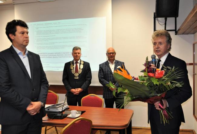 Burmistrz trzymający kwiaty, ze swoim zastępcą oraz przewodniczącym i wiceprzewodniczącym Rady Miejskiej 